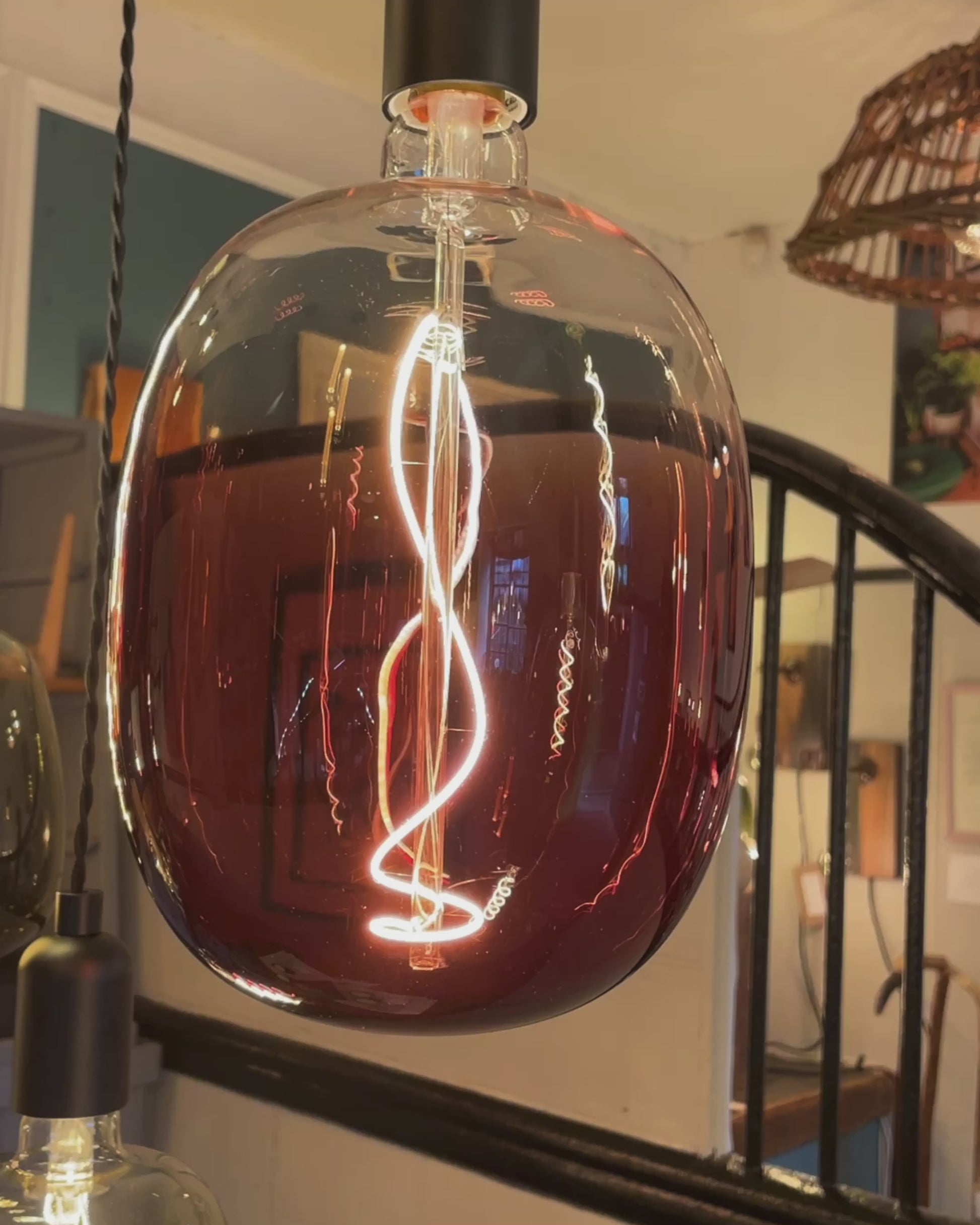 A video showing our rainbow chandelier. Seven lamp holders hang from a rustic canopy of reclaimed Norwegian Spruce timber. The cables are black fabric twisted, the lamp holder are smooth matte black. The chandelier features bulbs in amber, maroon and moss green.