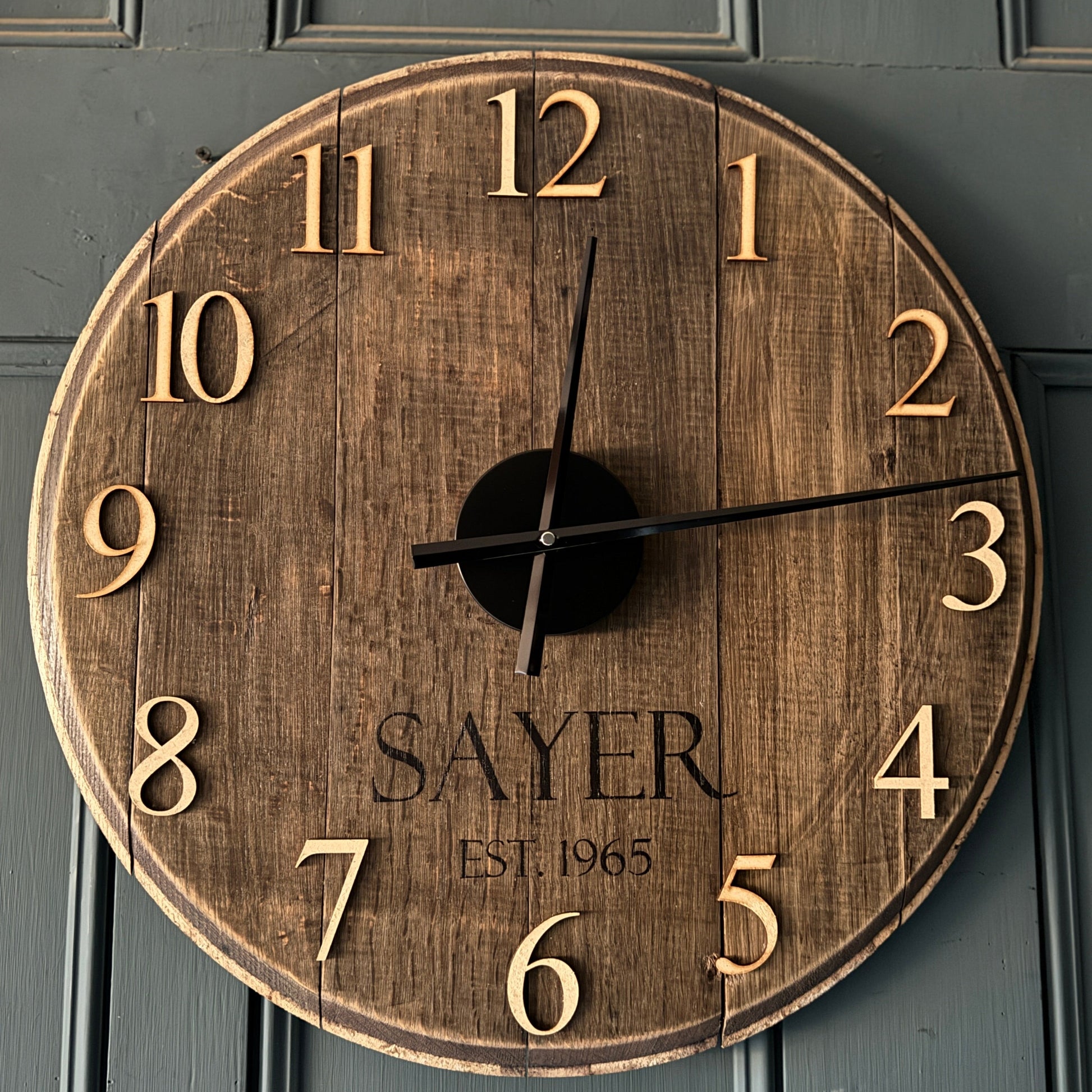 Personalised oak whiskey barrel clock handmade in Devon. Add a family name, birthday year or EST date. A unique reclaimed wood wall clock and perfect gift.