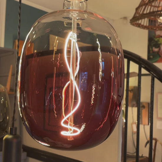 A video showing our rainbow chandelier. Seven lamp holders hang from a rustic canopy of reclaimed Norwegian Spruce timber. The cables are black fabric twisted, the lamp holder are smooth matte black. The chandelier features bulbs in amber, maroon and moss green.